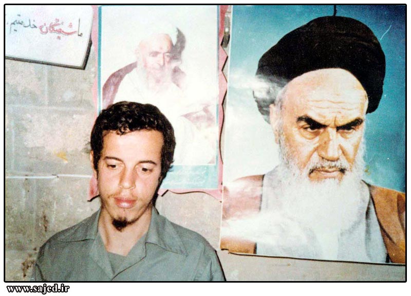 شهید حسن باقری در کنار تصویر امام خمینی(ره) — منبع: Wikimedia Commons